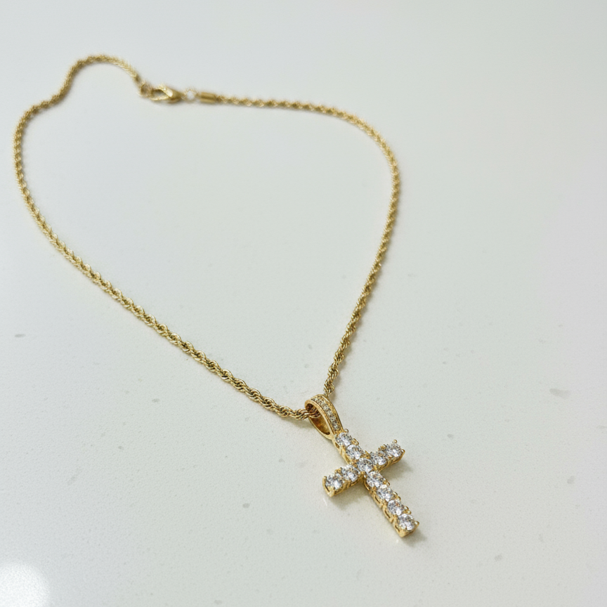 Gold diamond cross necklace with thinner chain on white counter