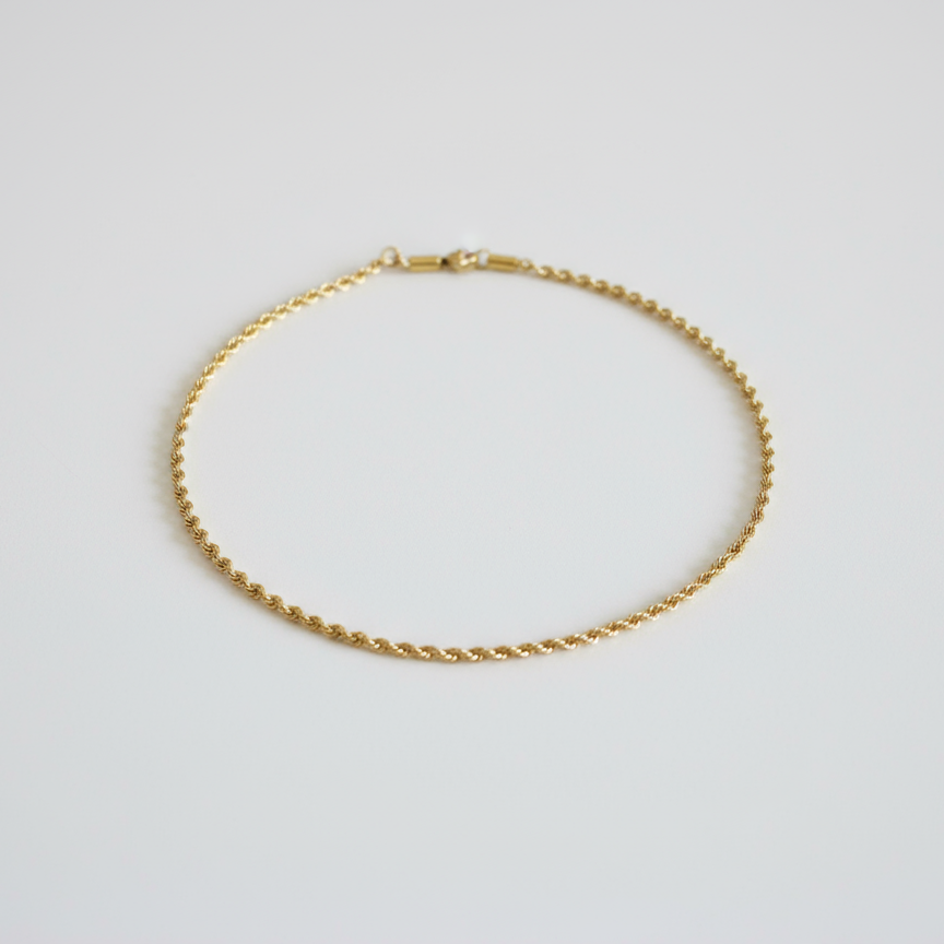 Gold rope chain necklace on white counter